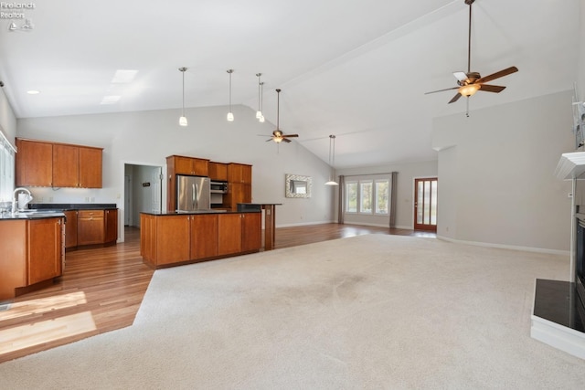 kitchen with brown cabinets, a ceiling fan, appliances with stainless steel finishes, and light carpet