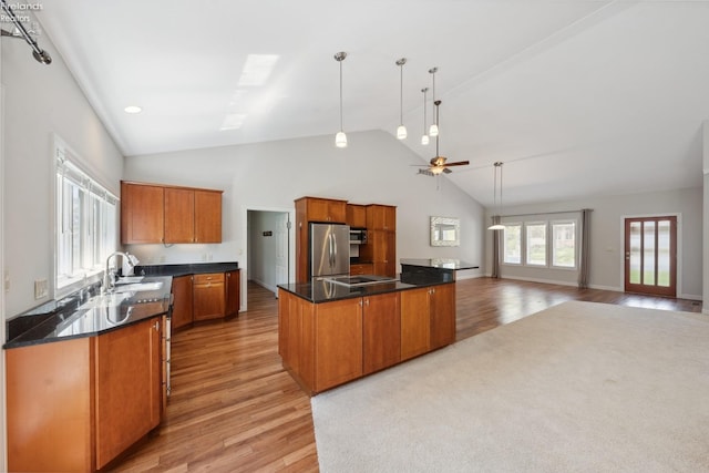 kitchen featuring dark countertops, light wood-style flooring, a center island, stainless steel appliances, and lofted ceiling