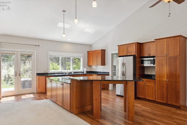 kitchen featuring brown cabinets, dark countertops, french doors, a center island, and stainless steel appliances