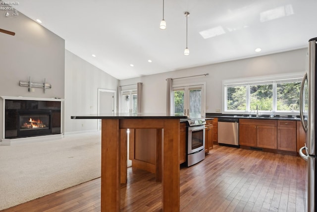 kitchen with light wood-style floors, dark countertops, brown cabinetry, and stainless steel appliances