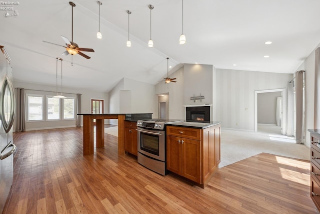 kitchen with brown cabinetry, a ceiling fan, open floor plan, stainless steel appliances, and lofted ceiling