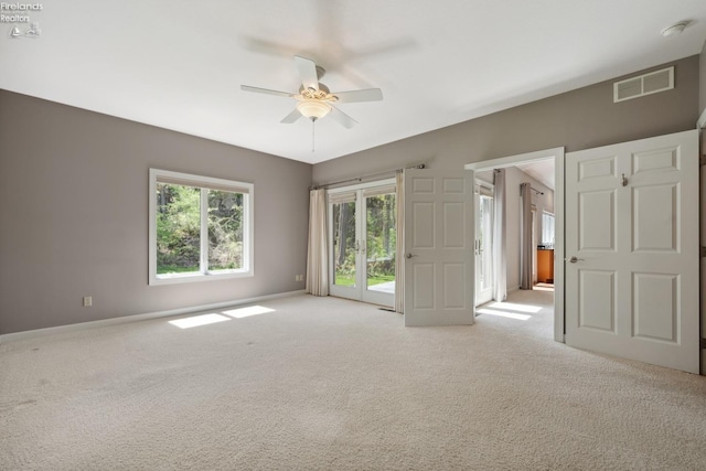 spare room featuring baseboards, ceiling fan, light colored carpet, and visible vents