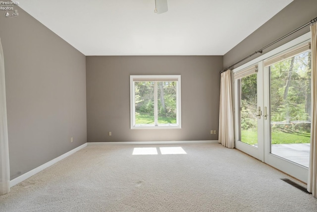 carpeted empty room featuring baseboards, a healthy amount of sunlight, and visible vents
