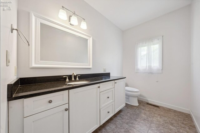 bathroom with vanity, baseboards, visible vents, and toilet