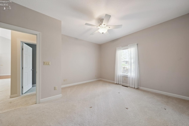 carpeted spare room with baseboards and a ceiling fan
