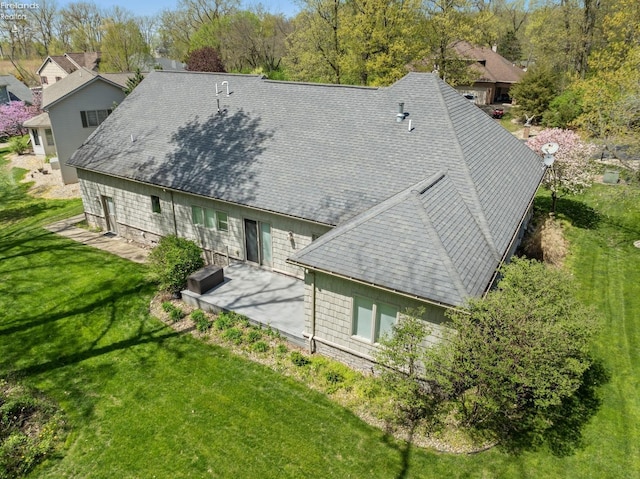 rear view of house featuring a lawn, a patio, and a shingled roof