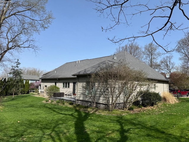 back of house featuring a lawn and a shingled roof