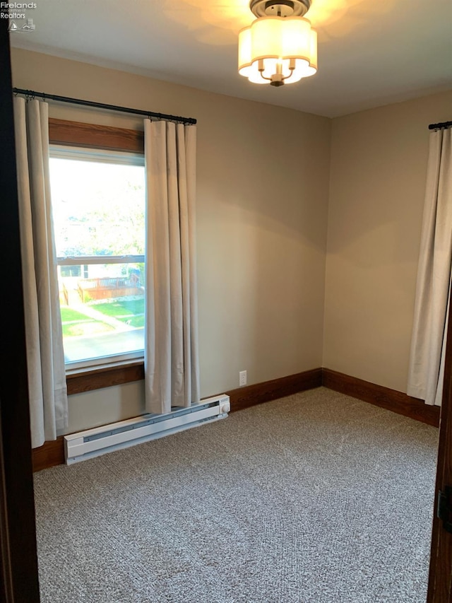 empty room featuring an inviting chandelier, baseboard heating, baseboards, and carpet floors