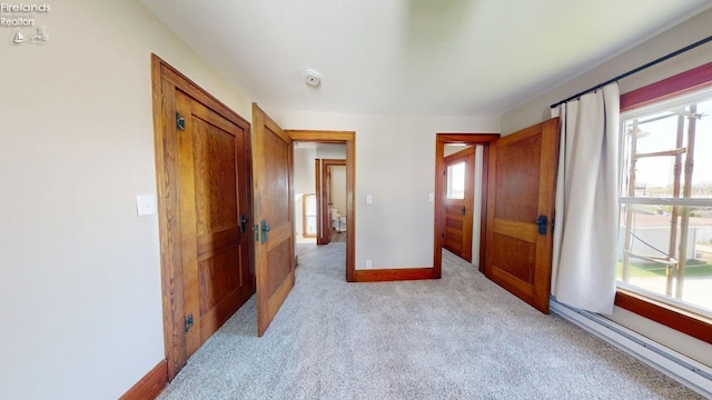 hallway with baseboards and light colored carpet