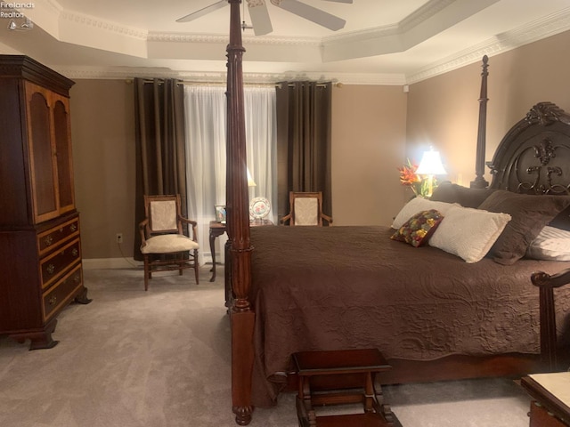 bedroom with ceiling fan, a tray ceiling, light colored carpet, and crown molding