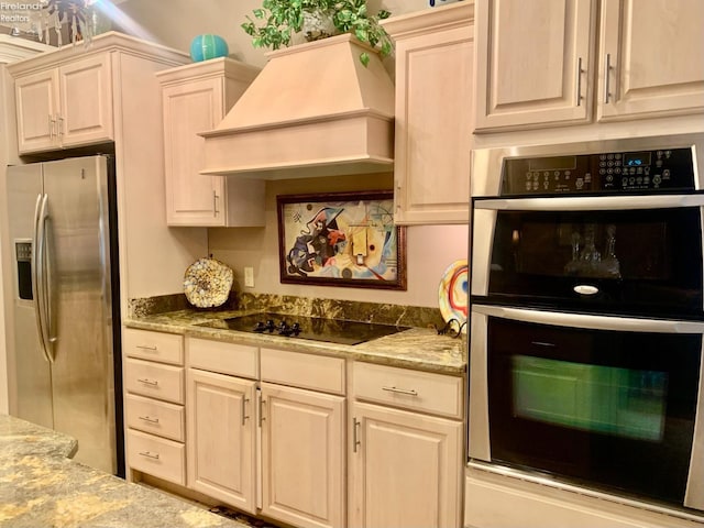 kitchen with light stone counters, stainless steel appliances, and custom range hood