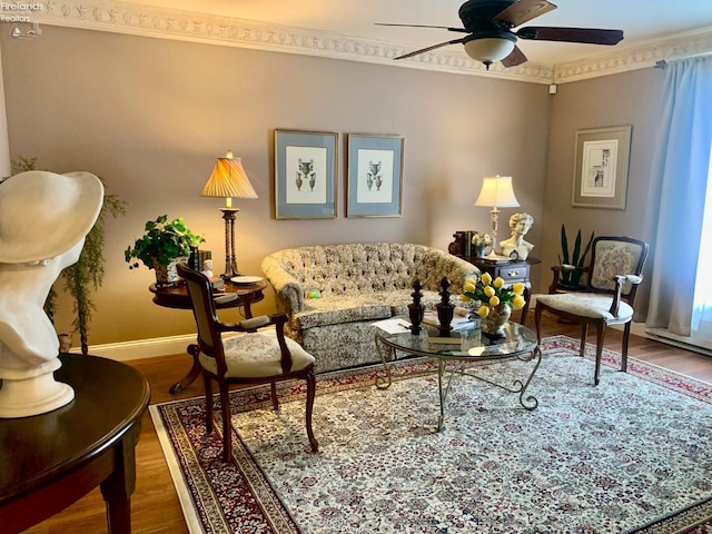 living area with ceiling fan, baseboards, crown molding, and wood finished floors