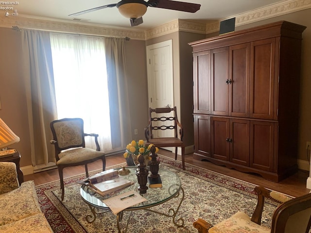living area with baseboards, wood finished floors, and ceiling fan