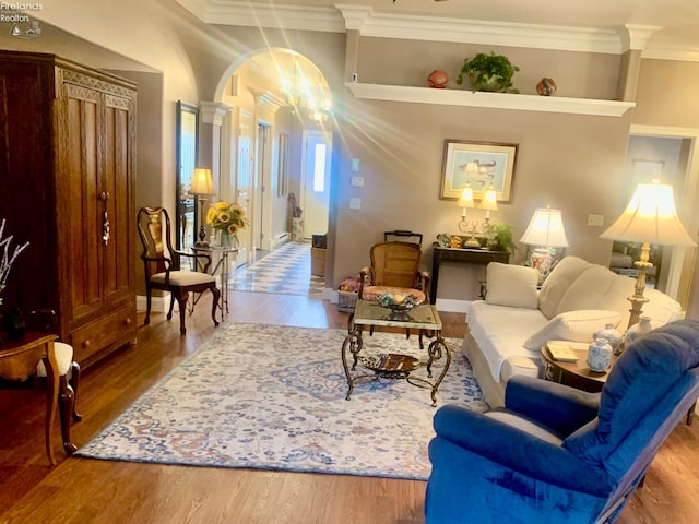 living room with wood finished floors, crown molding, and decorative columns