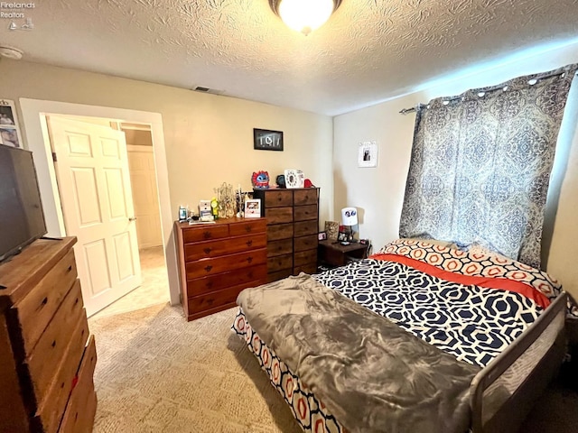 bedroom featuring a textured ceiling, visible vents, and carpet