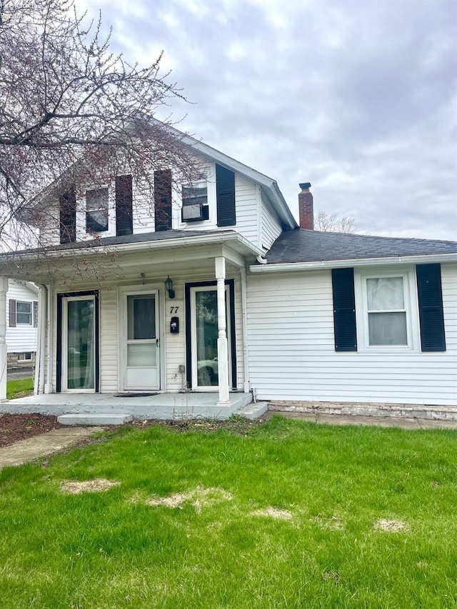 view of front of home featuring a chimney, a porch, and a front yard