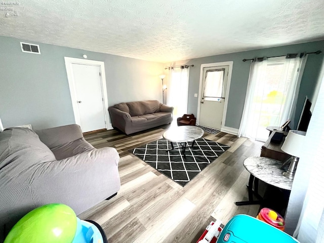 living area featuring a textured ceiling, visible vents, and wood finished floors