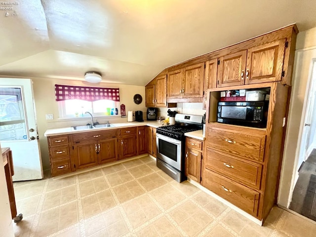 kitchen featuring gas stove, light countertops, brown cabinetry, and a sink