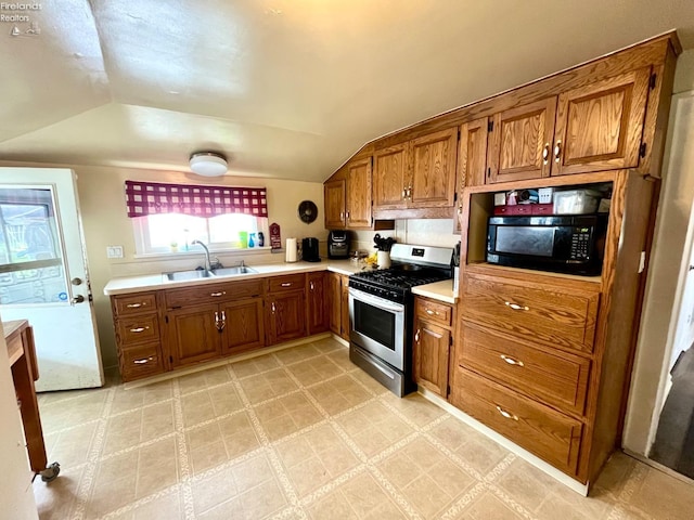 kitchen with a sink, brown cabinets, stainless steel gas range oven, and black microwave