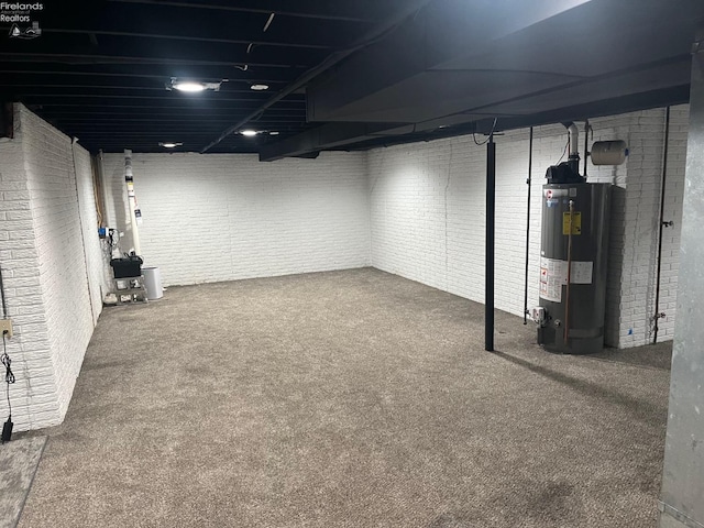 finished below grade area featuring brick wall, carpet floors, and gas water heater