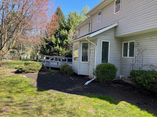 view of side of property featuring a lawn and a deck