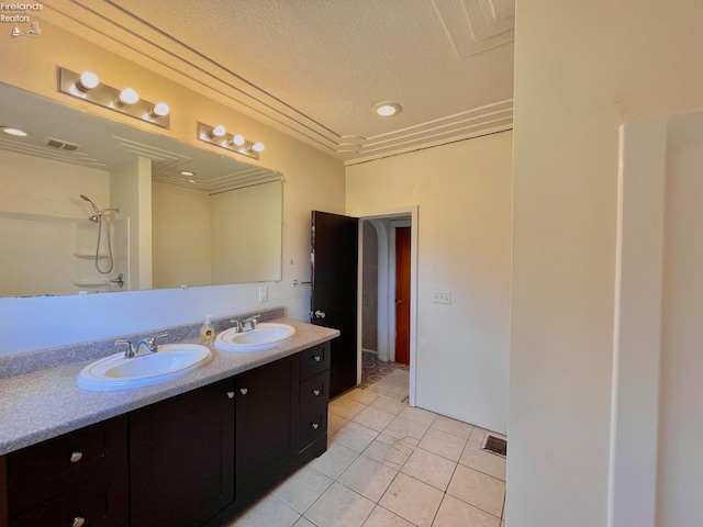 full bath with a textured ceiling, walk in shower, visible vents, and a sink