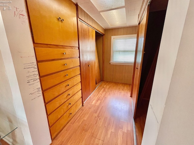 hallway featuring light wood-style floors and wooden walls