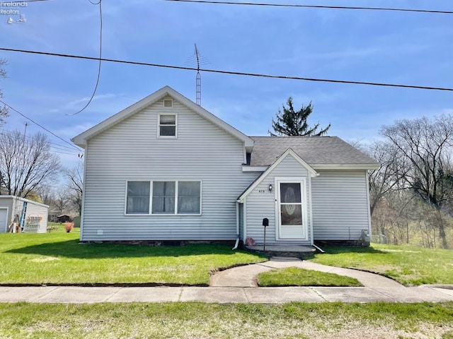 view of front of home featuring roof with shingles and a front yard