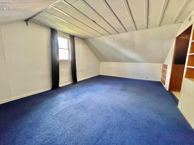 bonus room with dark carpet, vaulted ceiling, and baseboards