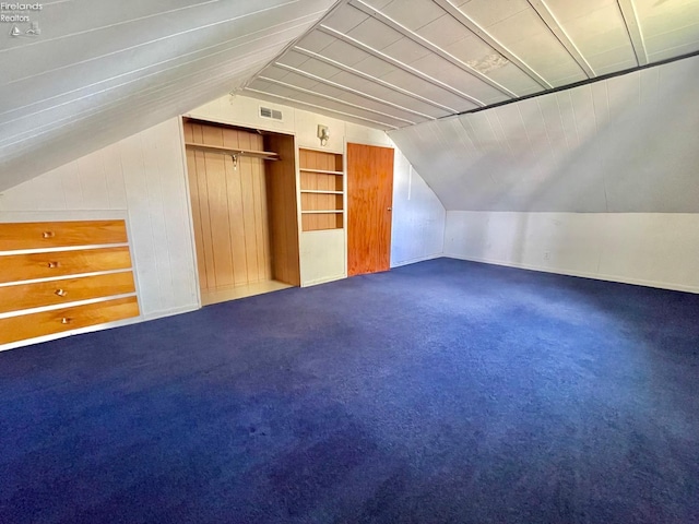 bonus room with wooden walls, vaulted ceiling, carpet floors, and visible vents