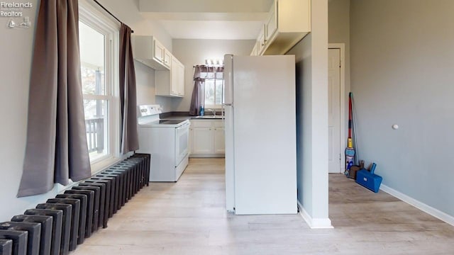 washroom with plenty of natural light, baseboards, a sink, and light wood-style flooring