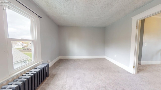 spare room with baseboards, carpet, and radiator