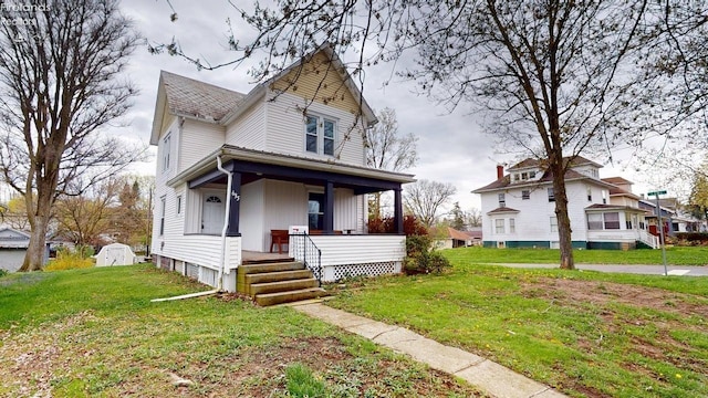 victorian house with a front yard, a shingled roof, and covered porch