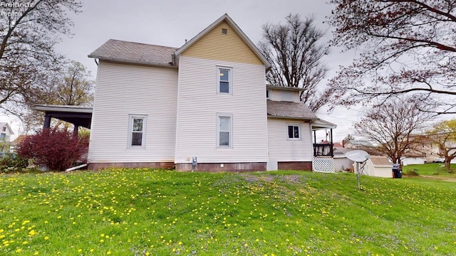 rear view of property featuring a lawn and a shingled roof