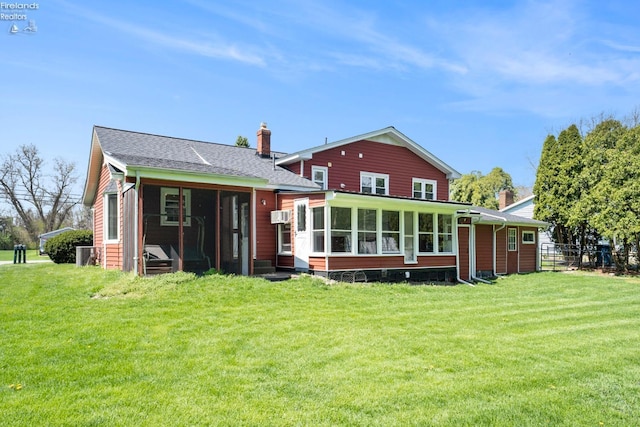 rear view of property with a chimney, a yard, a shingled roof, and a sunroom