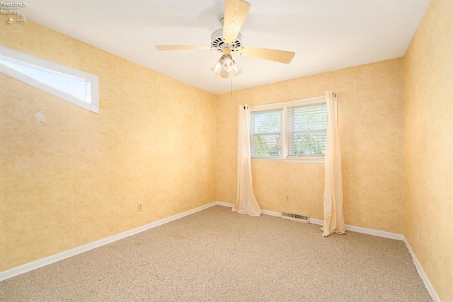 spare room with a ceiling fan, visible vents, light carpet, and baseboards