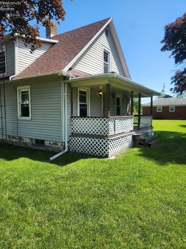 1501 E State St, Port Clinton, OH 43452 - view of side of property featuring covered porch, a lawn, a chimney, and a shingled roof