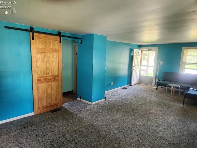 1501 E State St, Port Clinton, OH 43452 - unfurnished living room featuring carpet flooring, a barn door, and baseboards