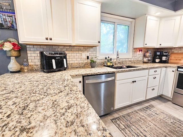 kitchen featuring backsplash, appliances with stainless steel finishes, a sink, and white cabinetry