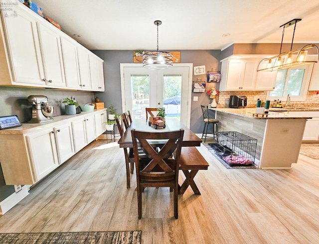 dining room with a healthy amount of sunlight, light wood finished floors, french doors, and an inviting chandelier