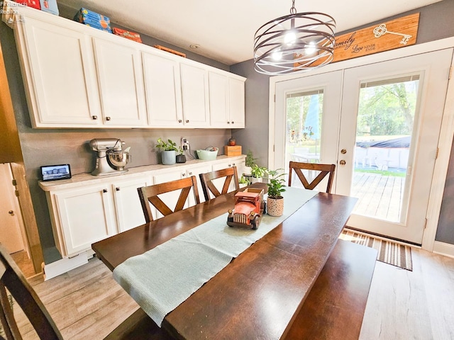 dining space with baseboards, a chandelier, and light wood-style flooring