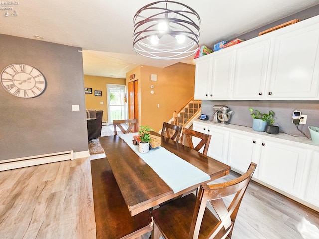 dining space featuring baseboard heating, light wood-style floors, and stairway