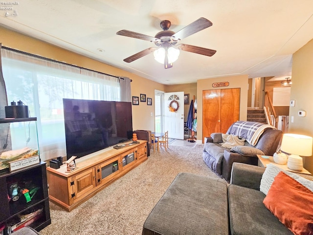 living area with stairway, carpet floors, and a ceiling fan