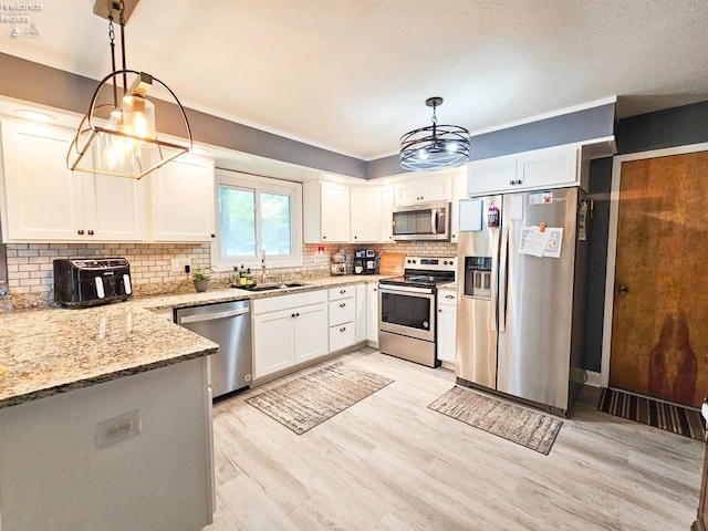 kitchen featuring a sink, light wood-style floors, a notable chandelier, light stone countertops, and appliances with stainless steel finishes