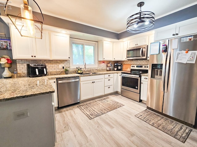 kitchen with light stone counters, a sink, a chandelier, light wood-style flooring, and appliances with stainless steel finishes