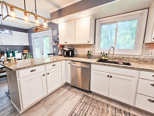 kitchen featuring dishwasher, a sink, a peninsula, light wood-style flooring, and white cabinetry