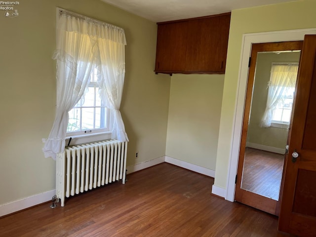 201 Gilcher Ct, Sandusky, OH 44870 - empty room featuring radiator, dark wood finished floors, a healthy amount of sunlight, and baseboards