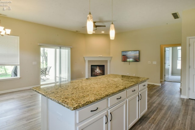 4340 E Mckenna Ln, Port Clinton, OH 43452 - kitchen with light wood-style flooring, a tiled fireplace, white cabinetry, hanging light fixtures, and open floor plan