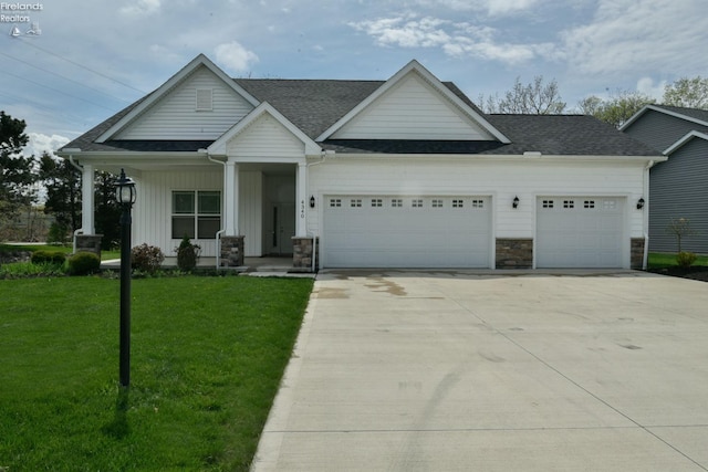 4340 E Mckenna Ln, Port Clinton, OH 43452 - view of front of property featuring a garage, concrete driveway, a front lawn, stone siding, and a shingled roof