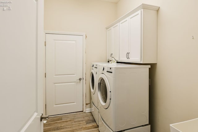 4340 E Mckenna Ln, Port Clinton, OH 43452 - laundry room featuring separate washer and dryer, light wood-type flooring, and cabinet space